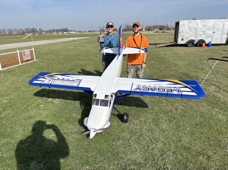 Two boys standing with a large-scale model airplane